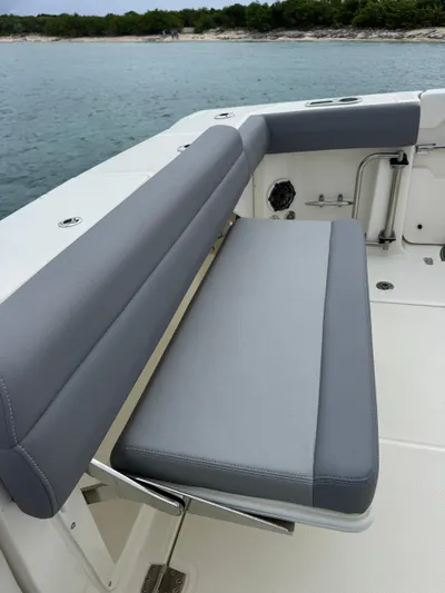  Yacht Photos Pics 2025 Boston Whaler 330 Outrage boat with gray cushioned seating, docked by the water.