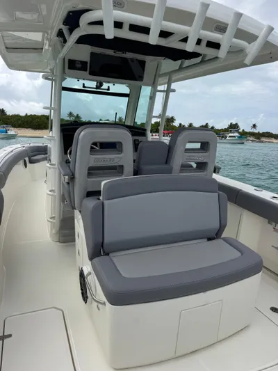  Yacht Photos Pics 2025 Boston Whaler 330 Outrage boat interior with gray seating, docked near a beach.