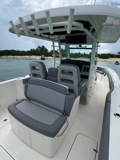  Yacht Photos Pics 2025 Boston Whaler 330 Outrage boat interior with seating and helm, near a scenic shoreline.