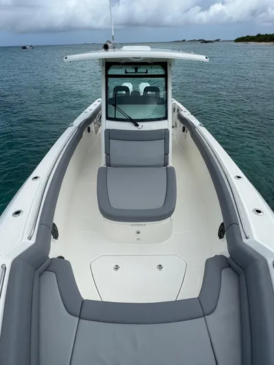  Yacht Photos Pics 2025 Boston Whaler 330 Outrage boat on calm water, featuring sleek design and spacious seating.