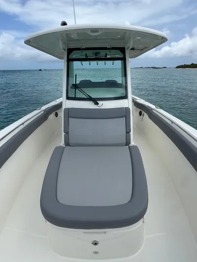  Yacht Photos Pics 2025 Boston Whaler 330 Outrage boat on calm water, featuring sleek design and spacious seating.