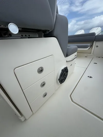  Yacht Photos Pics 2025 Boston Whaler 330 Outrage interior, featuring storage drawers and speaker, under a cloudy sky.