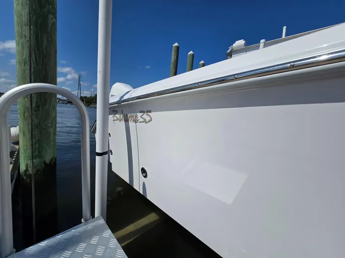  Yacht Photos Pics 2025 Bahama 35 Super Center Console docked by wooden posts, clear blue sky.