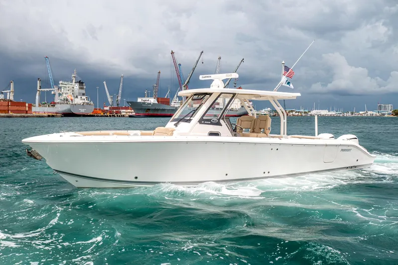 Southern Pass Yacht Photos Pics 2019 Pursuit S 328 Sport boat cruising in a busy harbor with stormy skies.