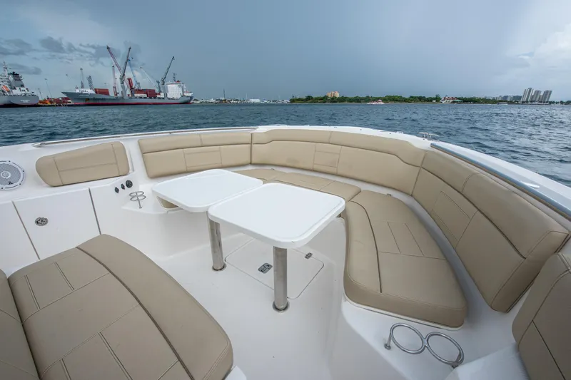 Southern Pass Yacht Photos Pics 2019 Pursuit S 328 Sport boat interior with beige seating and dual tables, docked near ships.