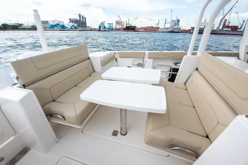 Southern Pass Yacht Photos Pics 2019 Pursuit S 328 Sport boat interior with beige seating and dual tables, dockside view.
