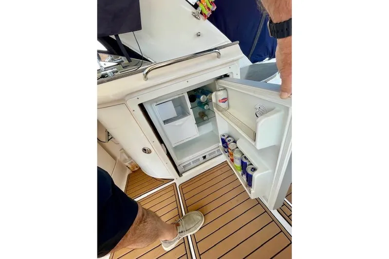 "just One Mohr" Yacht Photos Pics Open mini fridge on 2005 Regal Commodore 4260 boat, stocked with drinks on teak flooring.