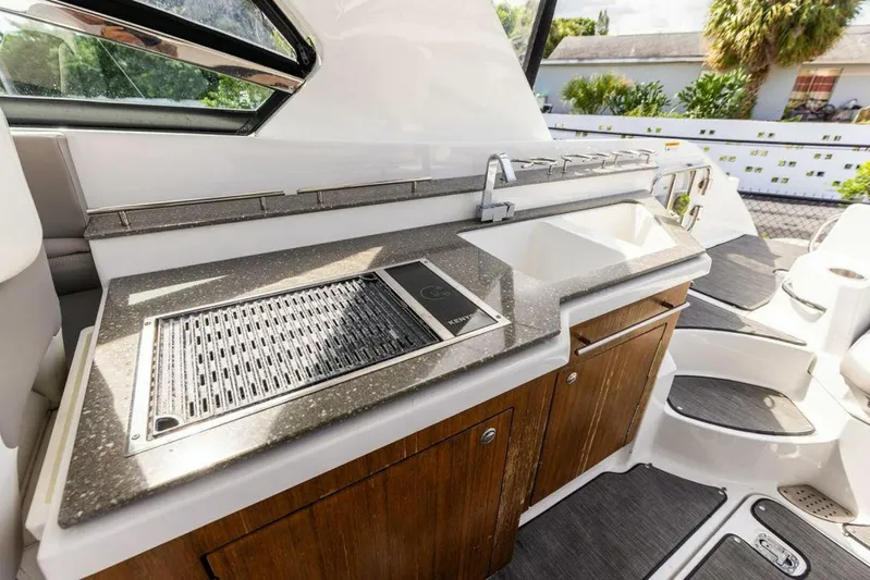  Yacht Photos Pics 2020 Four Winns H350 boat kitchen with grill and sink, featuring sleek design and wood cabinetry.