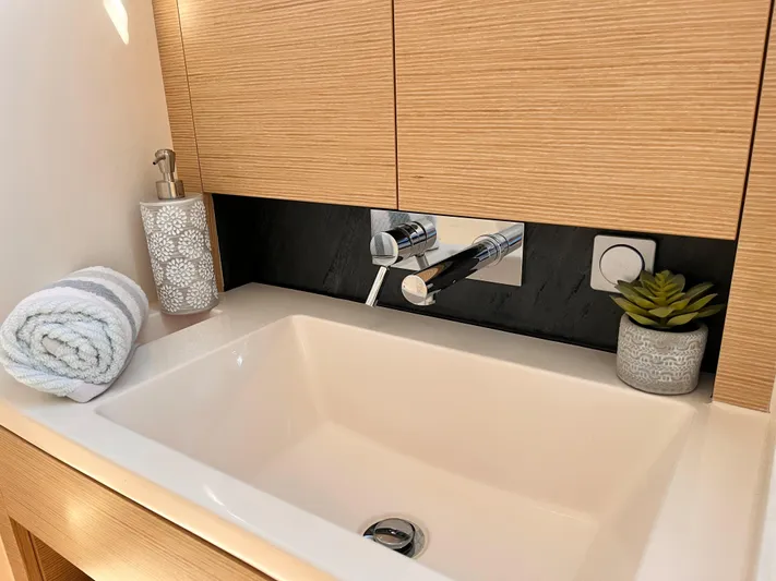 348 Sea Yacht Photos Pics Modern bathroom sink with wooden cabinetry, rolled towel, soap dispenser, and small plant. Hanse 348, 2026.