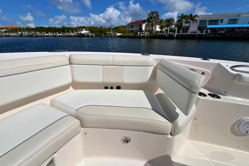 Perseverance Yacht Photos Pics 2019 Pursuit S 368 Sport boat interior with white seating, docked by waterfront homes.