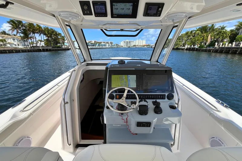 Perseverance Yacht Photos Pics 2019 Pursuit S 368 Sport boat cockpit with navigation system, steering wheel, and waterfront view.