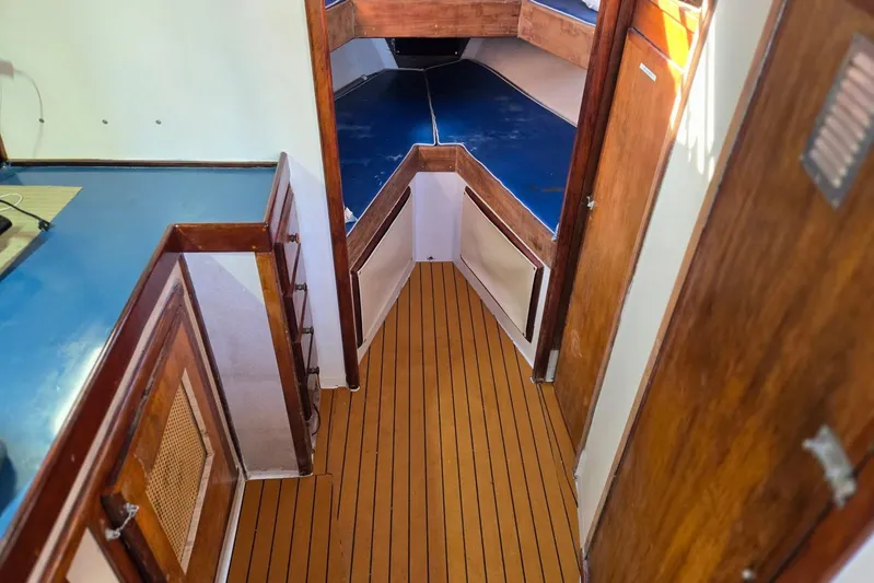 Sunrise Yacht Photos Pics 1995 MDI Downeast boat interior with wooden flooring and blue cushioned seating.