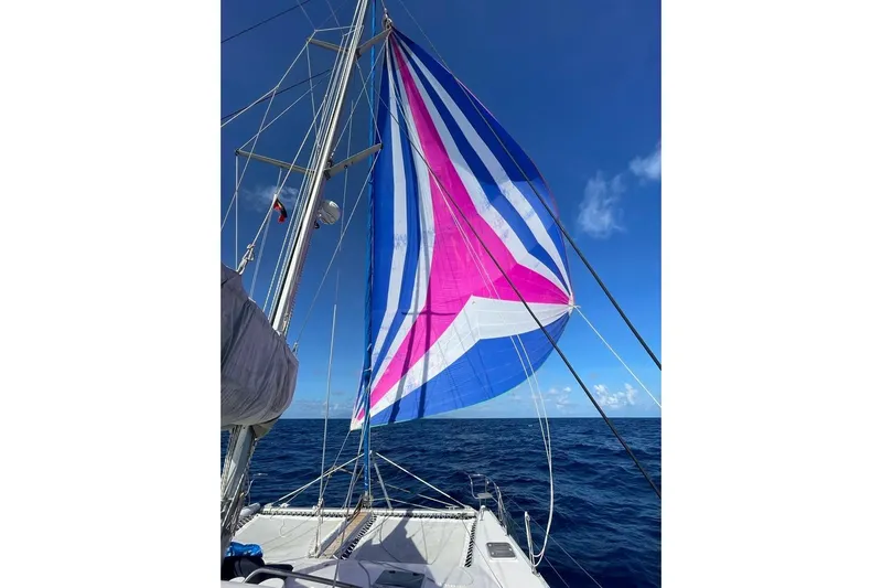  Yacht Photos Pics Sailboat Voyager Norseman 430 with colorful spinnaker sail on open sea, clear blue sky.