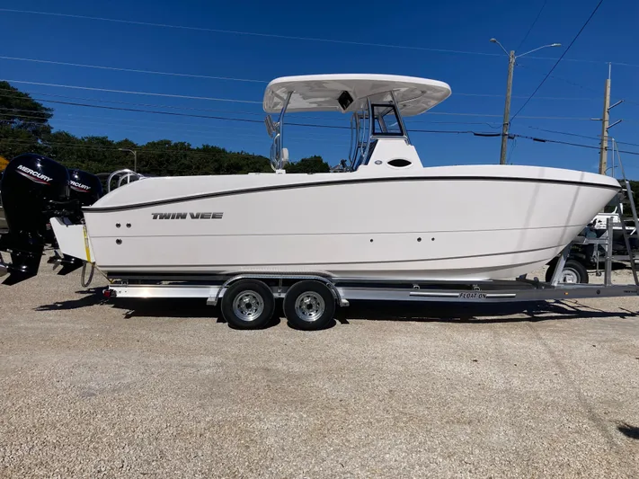  Yacht Photos Pics 2025 Twin Vee 260STX boat on trailer, side view, clear sky background.