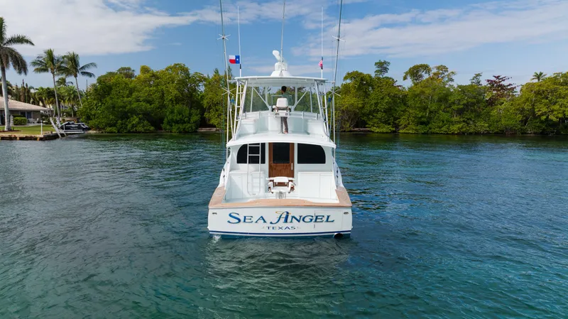 Sea Angel Yacht Photos Pics 1980 Scarborough 46 Convertible boat named "Sea Angel" on calm water, surrounded by lush greenery.