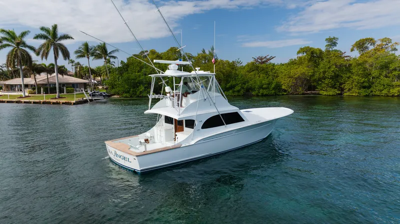 Sea Angel Yacht Photos Pics 1980 Scarborough 46 Convertible yacht on serene water, surrounded by lush greenery and palm trees.