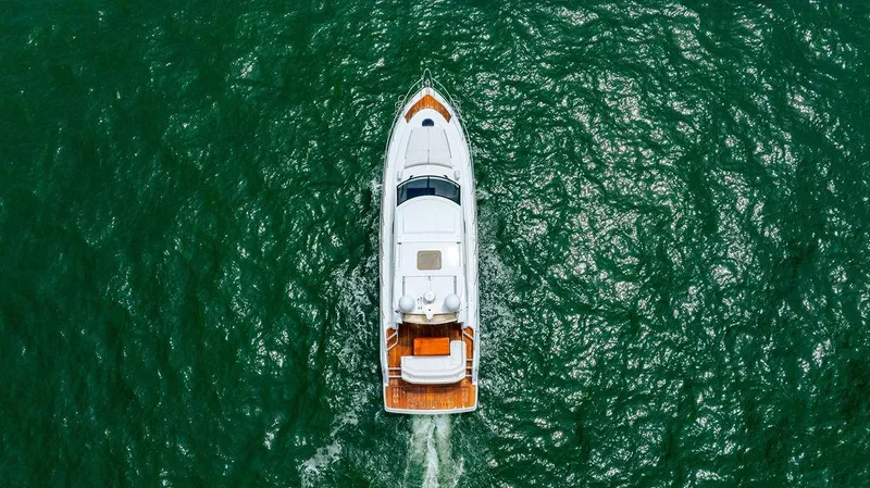 The Royal Blue Yacht Photos Pics Aerial view of 2015 Beneteau GRAN TURISMO 49 yacht cruising on green water.