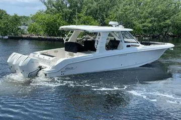 Yacht Photos Pics 2022 Boston Whaler 350 Realm cruising on a calm waterway surrounded by greenery.