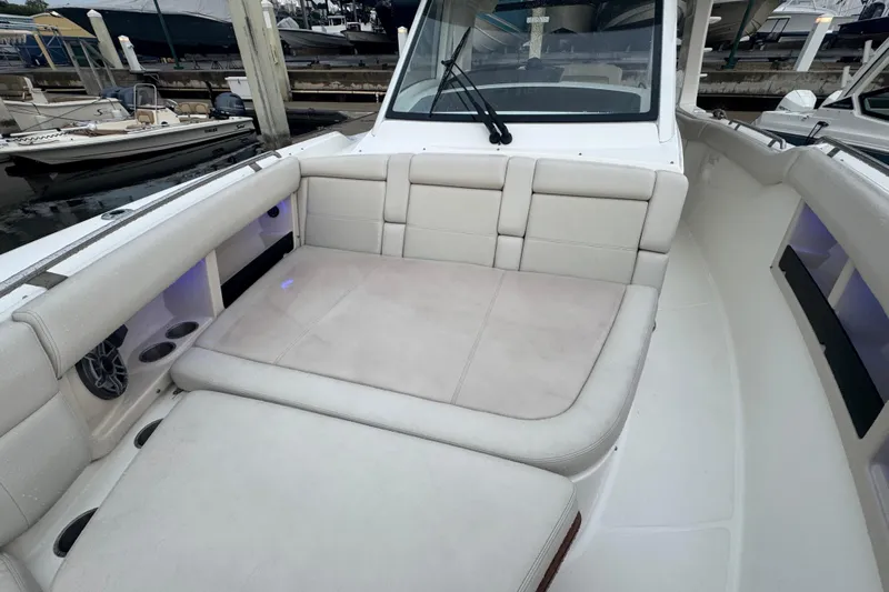  Yacht Photos Pics 2022 Boston Whaler 350 Realm boat interior with cushioned seating in a marina setting.