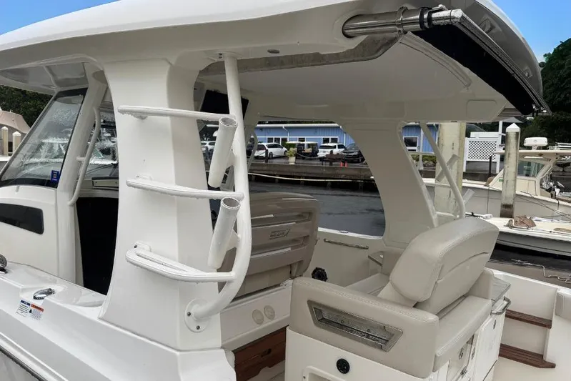  Yacht Photos Pics 2022 Boston Whaler 350 Realm boat interior with seating and rod holders at a marina.