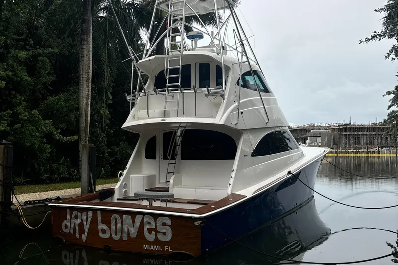 Dry Bones Yacht Photos Pics 2017 Viking 66 Enclosed Bridge yacht docked in Miami, surrounded by lush greenery.