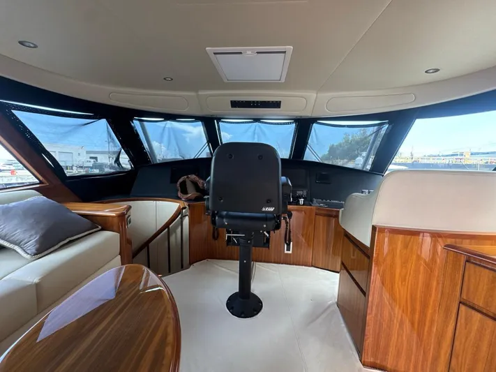 Dry Bones Yacht Photos Pics Luxurious interior of 2017 Viking 66 Enclosed Bridge yacht with captain's chair and panoramic windows.