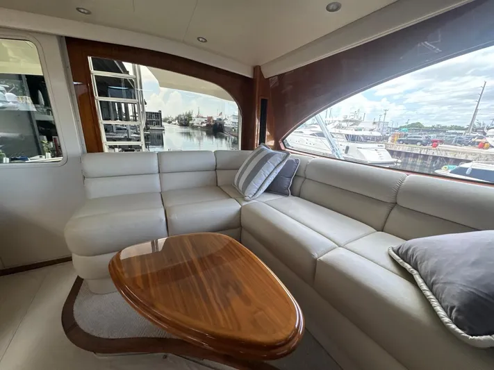 Dry Bones Yacht Photos Pics Luxurious interior of 2017 Viking 66 Enclosed Bridge yacht with plush seating and wooden table.