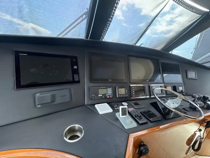Dry Bones Yacht Photos Pics Control panel of 2017 Viking 66 Enclosed Bridge yacht with multiple screens and steering wheel.