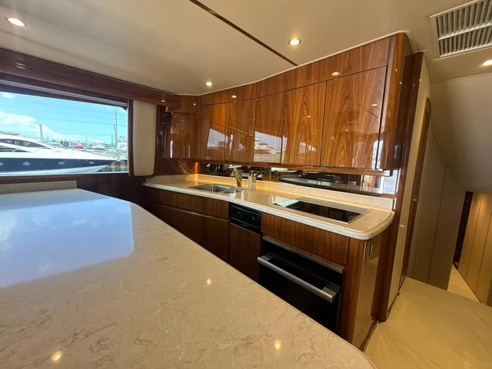Dry Bones Yacht Photos Pics Luxurious kitchen interior of 2017 Viking 66 Enclosed Bridge yacht with wood cabinetry and modern appliances.