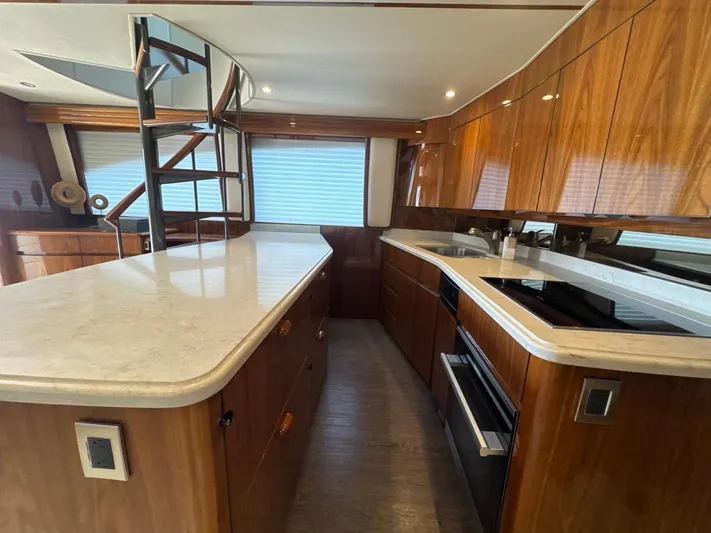 Dry Bones Yacht Photos Pics Luxurious kitchen interior of 2017 Viking 66 Enclosed Bridge yacht with wooden cabinetry and modern appliances.
