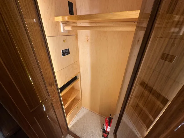 Dry Bones Yacht Photos Pics 2017 Viking 66 Enclosed Bridge yacht interior closet with wooden shelves and fire extinguisher.