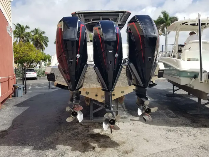 Power Slave Yacht Photos Pics 2020 Nor-Tech Center Console boat with triple outboard engines, docked outdoors.