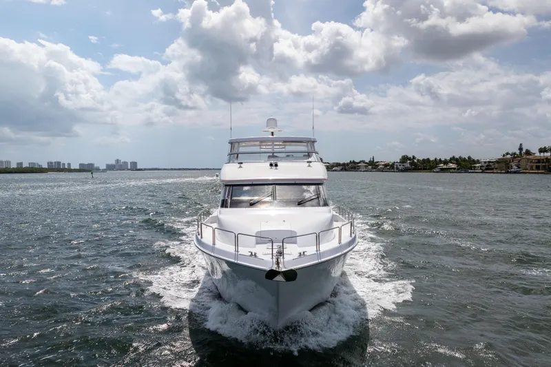 Outrageous Yacht Photos Pics 2005 Hatteras 80 Motor Yacht cruising on a sunny day, surrounded by calm waters.