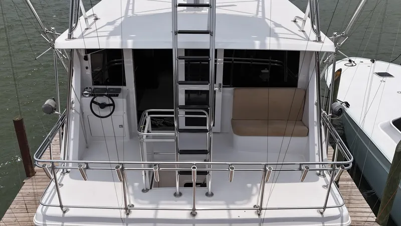 Poco Mas Yacht Photos Pics 1996 Donzi Custom Enclosed Flybridge yacht docked, rear view showing ladder and seating area.