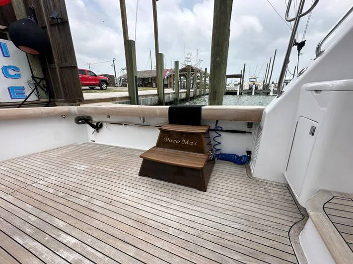 Poco Mas Yacht Photos Pics 1996 Donzi Custom Enclosed Flybridge boat deck with wooden steps at a marina.