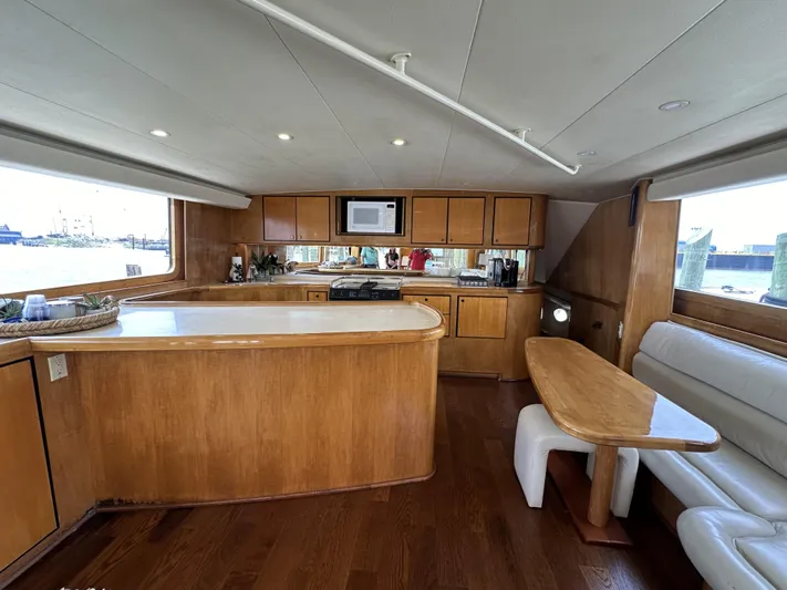 Poco Mas Yacht Photos Pics Interior of 1996 Donzi Custom Enclosed Flybridge with wooden cabinetry and dining area.