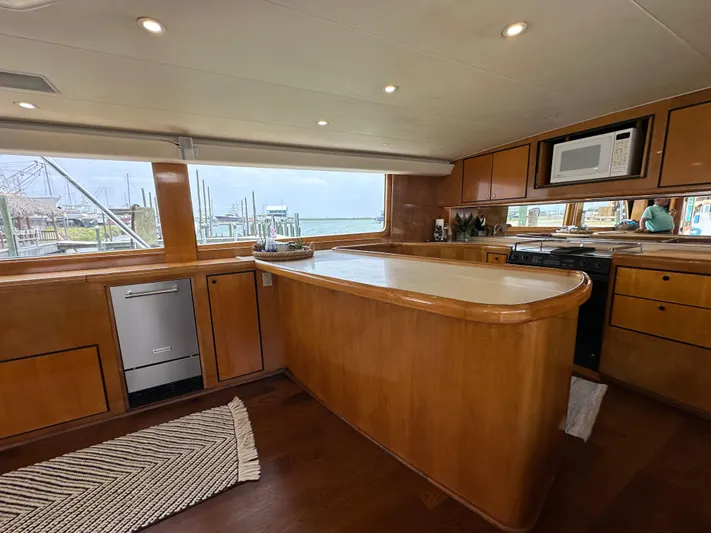 Poco Mas Yacht Photos Pics 1996 Donzi Custom Enclosed Flybridge kitchen with wooden cabinetry and modern appliances.