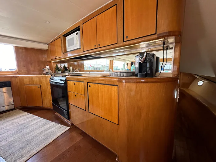 Poco Mas Yacht Photos Pics 1996 Donzi Custom Enclosed Flybridge kitchen with wooden cabinets and modern appliances.