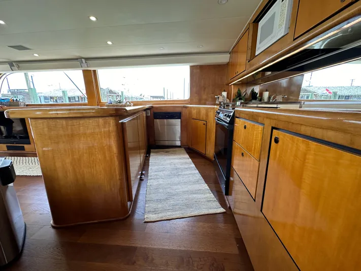 Poco Mas Yacht Photos Pics 1996 Donzi Custom Enclosed Flybridge kitchen with wooden cabinetry and modern appliances.