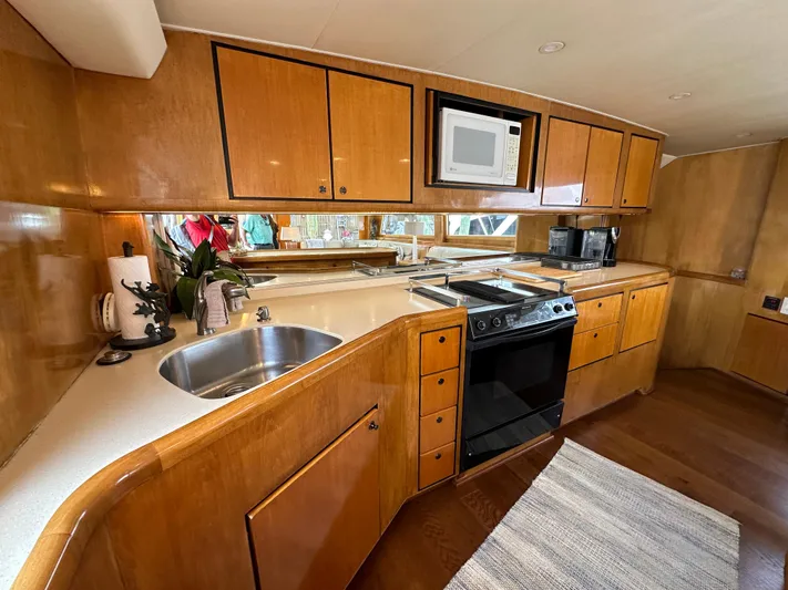 Poco Mas Yacht Photos Pics 1996 Donzi Custom Enclosed Flybridge kitchen with wood cabinetry, stove, microwave, and sink.