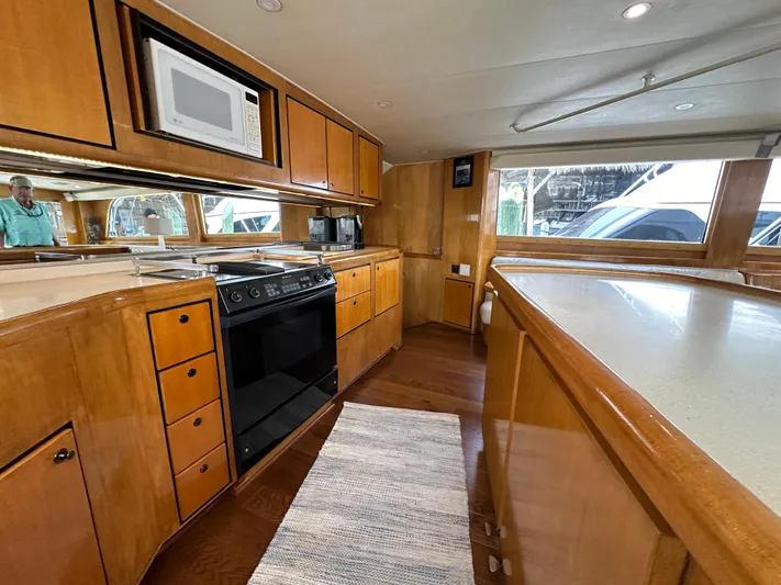 Poco Mas Yacht Photos Pics 1996 Donzi Custom Enclosed Flybridge kitchen with wooden cabinets, stove, microwave, and ample counter space.