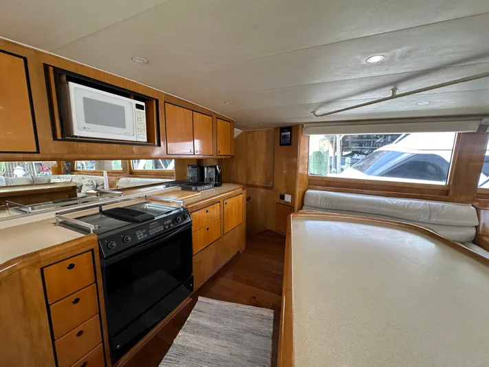 Poco Mas Yacht Photos Pics 1996 Donzi Custom Enclosed Flybridge kitchen with microwave, stove, and wooden cabinetry.