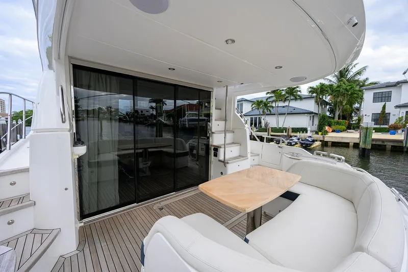  Yacht Photos Pics Luxurious 2022 Princess F50 yacht deck with seating and table, docked by waterfront homes.