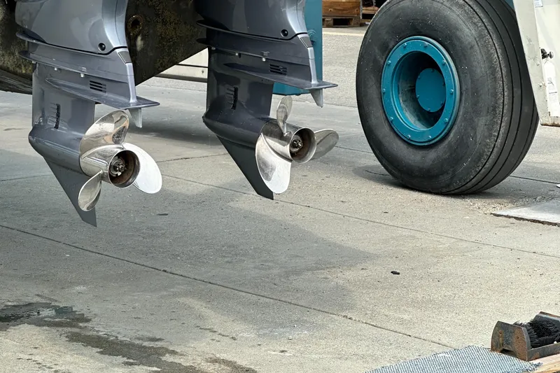  Yacht Photos Pics 2023 Sportsman Open 282 Center Console boat propellers and trailer wheel on concrete surface.