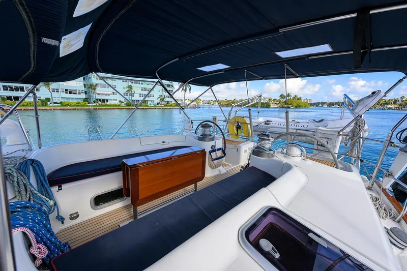 Windigo Yacht Photos Pics Spacious cockpit of 2003 Beneteau 50 yacht with blue canopy, docked by waterfront buildings.