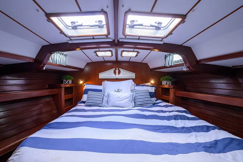 Windigo Yacht Photos Pics Luxurious cabin interior of a 2003 Beneteau 50 yacht with striped bedding and wooden accents.
