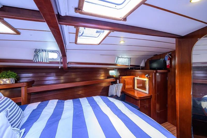 Windigo Yacht Photos Pics Luxurious cabin interior of 2003 Beneteau 50 yacht with striped bedding and wooden finishes.