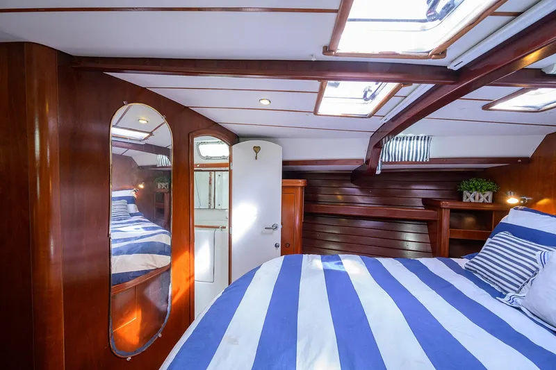 Windigo Yacht Photos Pics Luxurious cabin interior of 2003 Beneteau 50 yacht with striped bedding and wooden finishes.