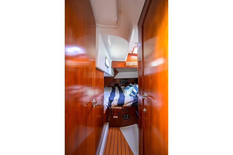 Windigo Yacht Photos Pics Cozy cabin interior of 2003 Beneteau 50 yacht with wooden finish and striped bedding.