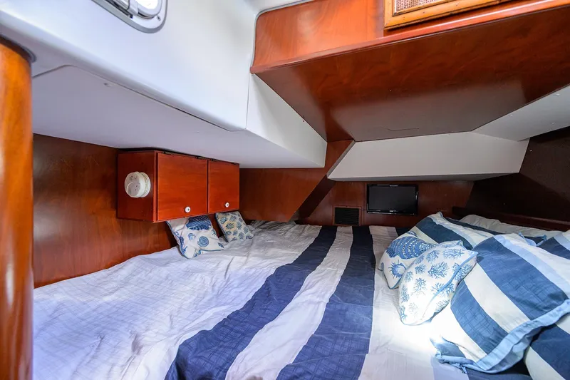 Windigo Yacht Photos Pics Cozy cabin interior of 2003 Beneteau 50 yacht with striped bedding and wooden cabinetry.